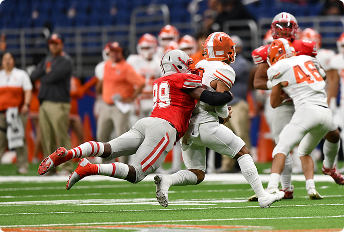 american football orange and red teams with runner being tackled