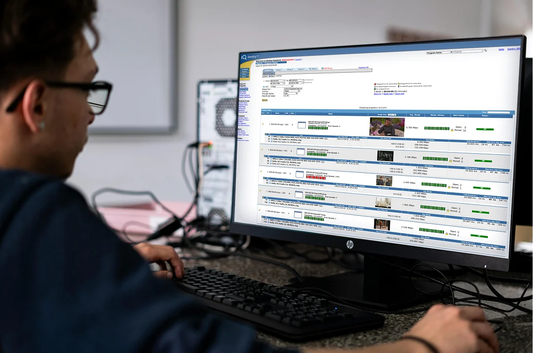 Person working at a desk with a computer monitor displaying a media monitoring interface
