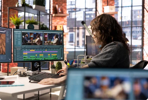 Person working at a desk in a modern office environment using a computer with dual monitors