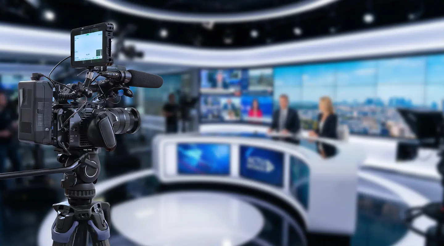 Broadcast camera filming anchors on a modern TV news set
